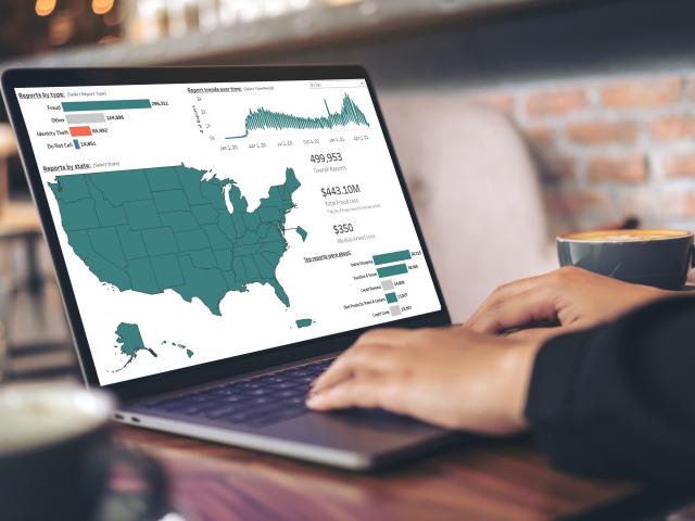 Close up of someone working on laptop with U.S. map of fraud reports displayed