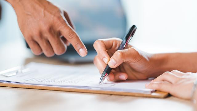 hand pointing to another hand signing a contract